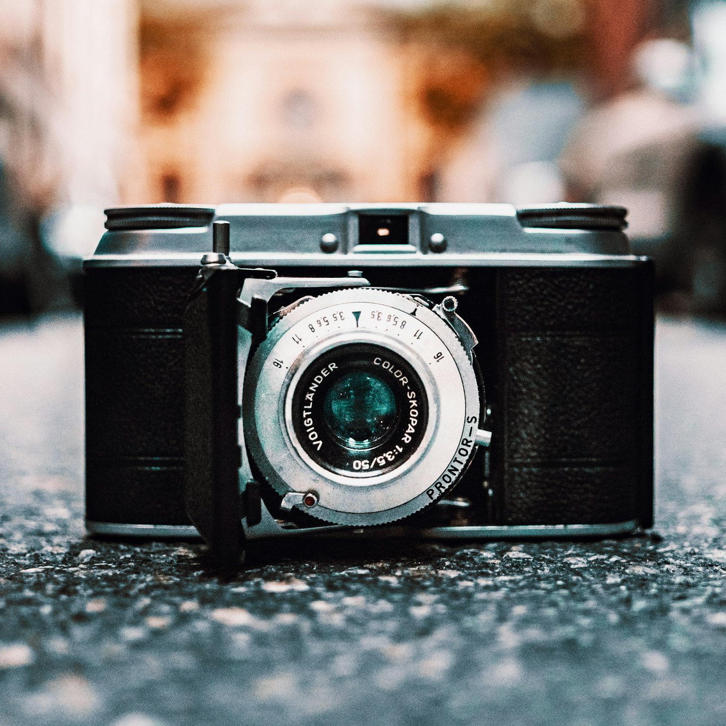 En vintage Voigtländer hopfällbar kamera på grå asfalt.